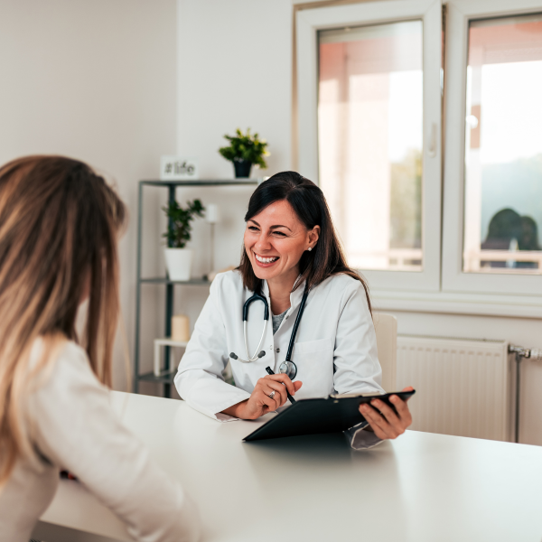 Advanced practice provider speaking with a patient and referencing a tablet during a clinical visit