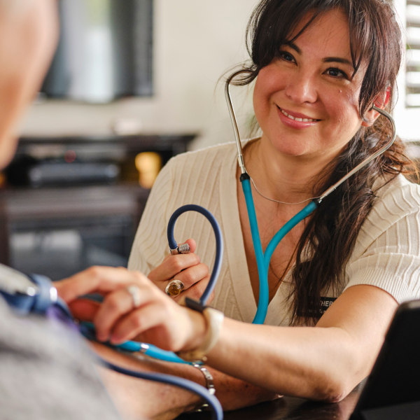 Advanced practice provider using a stethoscope while interacting with a patient on the job.